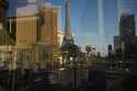 Reflected in a glass window, people walk across a pedestrian bridge along the Las Vegas Strip, Frid…