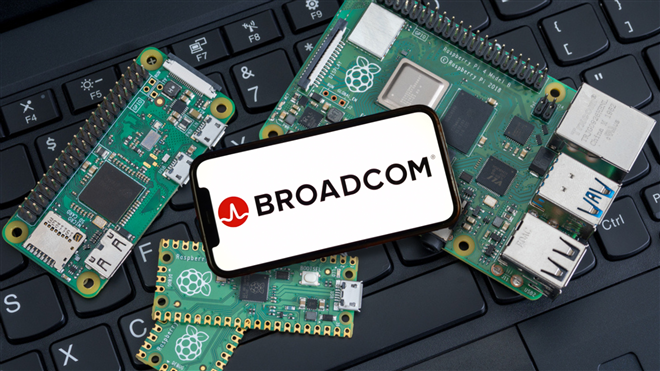 Broadcom logo on cellphone with chip boards on keyboard - This image is an original composition by MarketBeat using licensed and editorial elements. Not for redistribution or reuse.